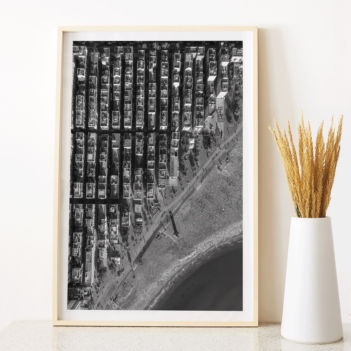 Aerial cityscape and black and white poster of Barceloneta beach and city grid aerial view, framed and displayed in modern living room decor