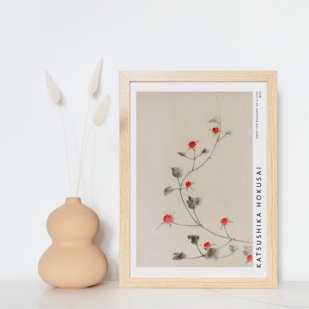 Small Red Blossoms on a Vine artwork by Katsushika Hokusai featuring delicate red flowers and green leaves on a light background, framed and displayed in home decor