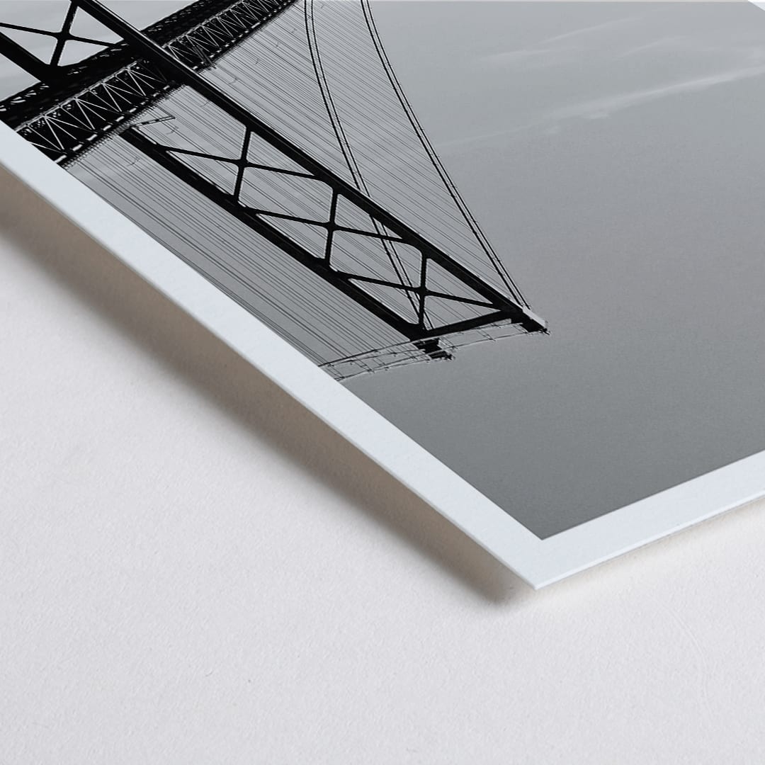 Closeup detail of Lisbon Bridge Black and White Poster by Raphael Alves featuring a framed photograph of a suspension bridge and sailboat in the water