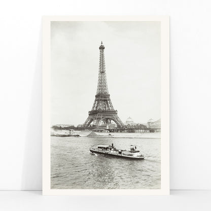 Black and white photograph and poster of the Eiffel Tower in Paris with a vintage boat on the Seine river wall decor artwork, framed and displayed in modern living room decor