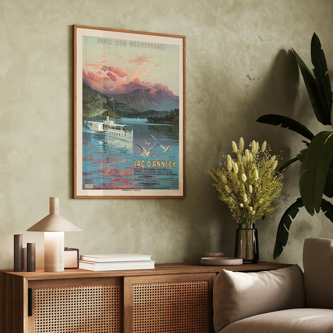 Poster of Le Lac d Annecy by Frederic Hugo d Alesi showing a scenic mountain lake with boat and seagulls at sunset, framed and displayed in home decor