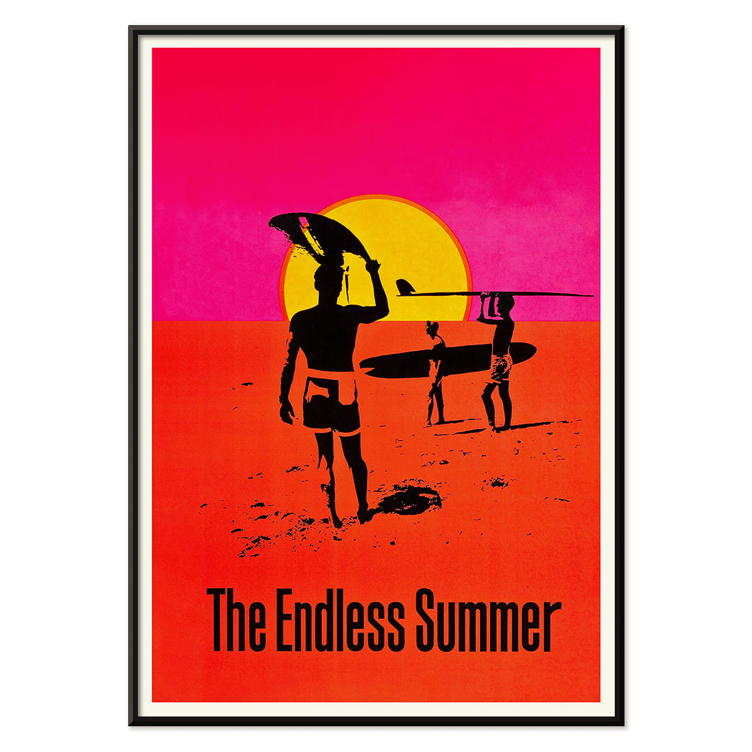 The Endless Summer poster with surfers carrying boards on a beach at sunset against a stylized sunset backdrop, with black aluminium frame on white background